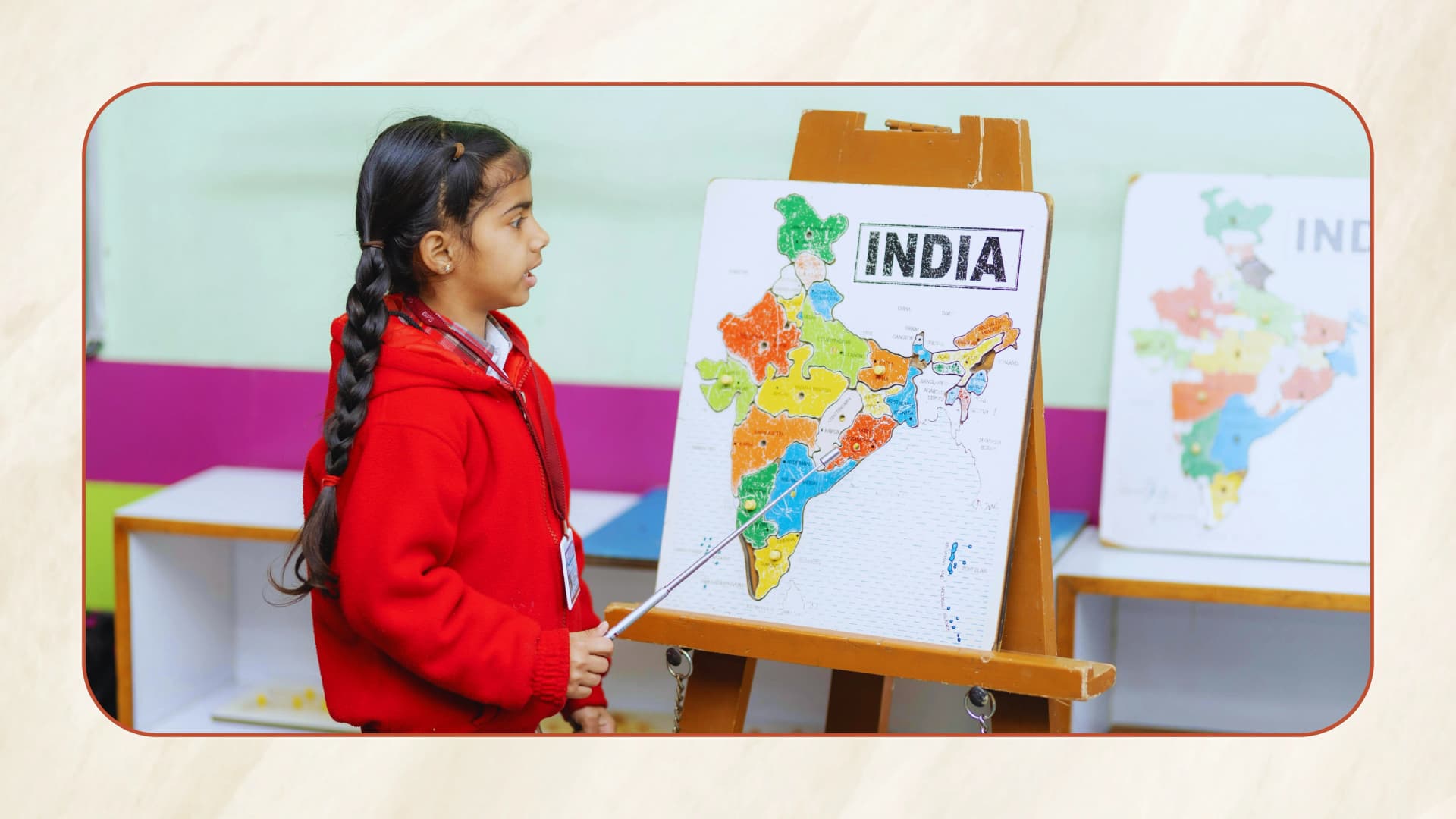 A girl pointing at a map of India on an easel during a geography lesson.