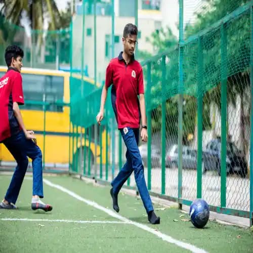 Two boys in Orchids school uniform playing football on the field, showcasing teamwork and sportsmanship.