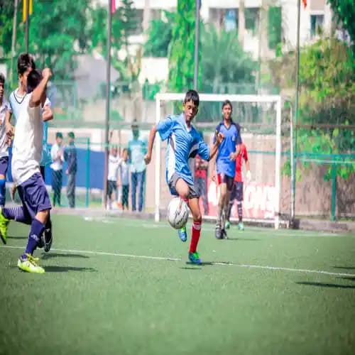 Boys in Orchids school uniform playing football on the field, showcasing their skills and teamwork during an exciting match.
