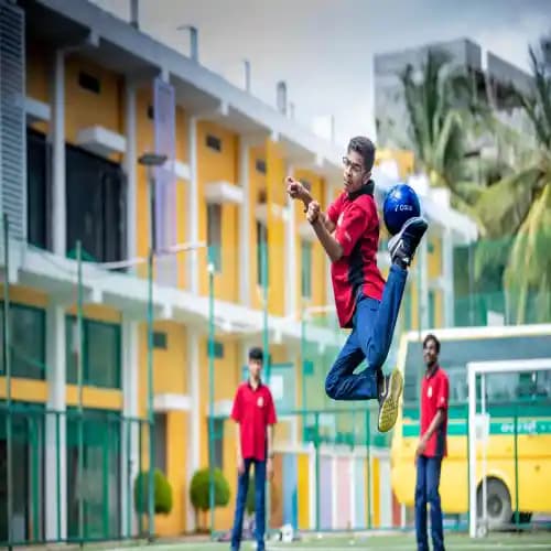 A young boy in a red shirt performing an acrobatic kick with a blue soccer ball while playing outdoors, with friends watching in the background.