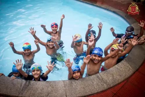Group of kids swimming & having fun in the school pool, enjoying their swimming lesson with laughter & excitement.