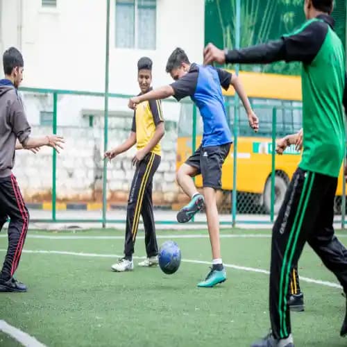 Group of boys playing football on the school field at Orchids, enjoying an energetic match with teamwork & enthusiasm.