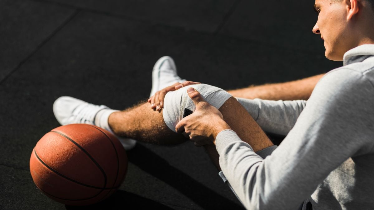 basketball-player-applying-bandage-knee