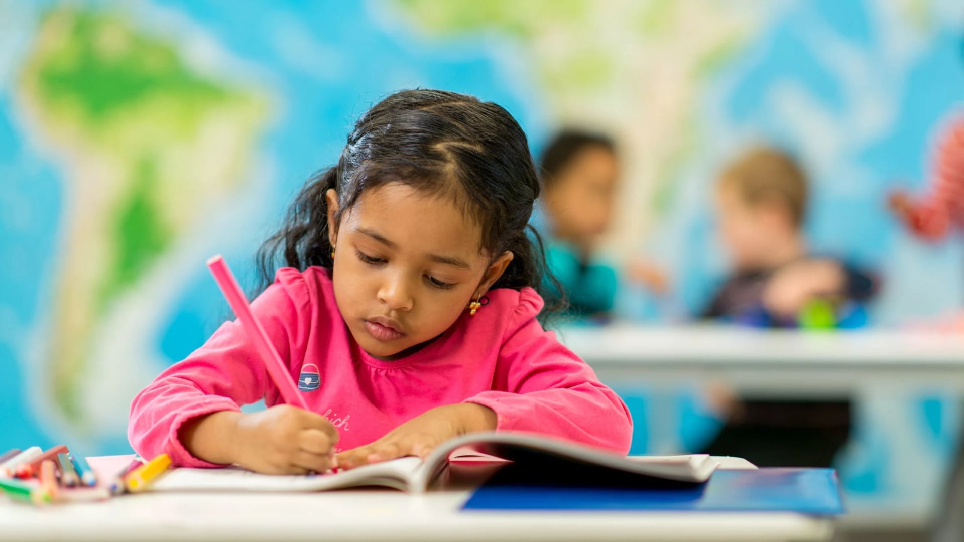 Young girl writing in a notebook, symbolizing focused learning for vocabulary improvement through word games.