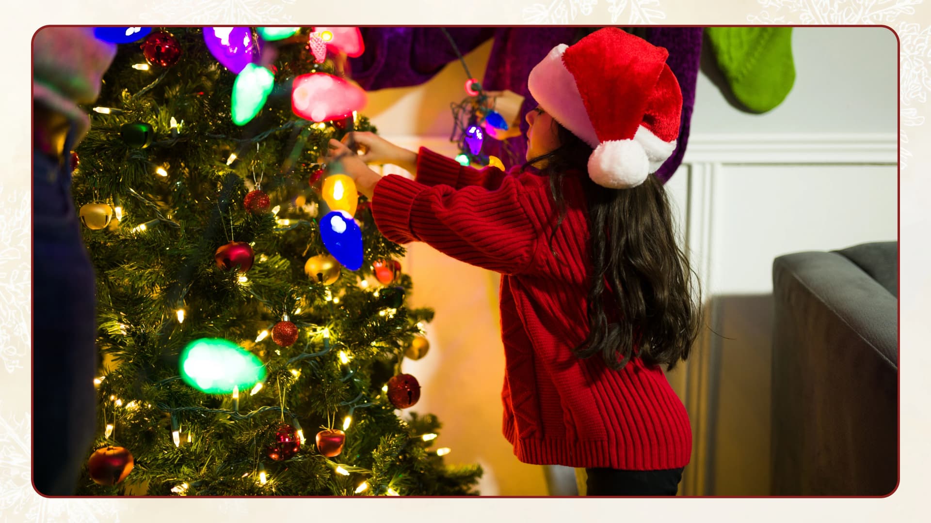 From cane candy to baubles and stars: All you need to decorate the Christmas tree! A child wearing a Santa hat decorates a Christmas tree with colourful lights and ornaments indoors.